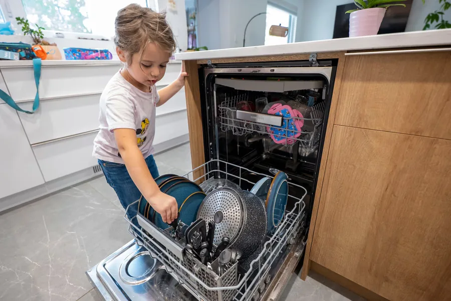 Lùcia, une petite fille, vide le lave-vaisselle dans la cuisine familiale
